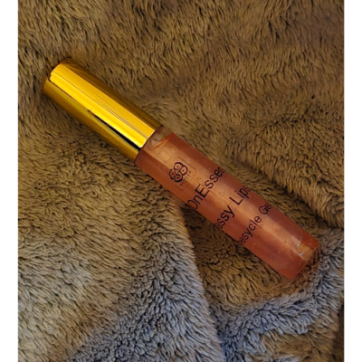Elixian Essence lip gloss bottle lying flat, showcasing its elegant design