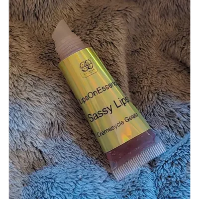Elixian Essence lip gloss squeeze tube with the lid off, showing the applicator tip for controlled dispensing